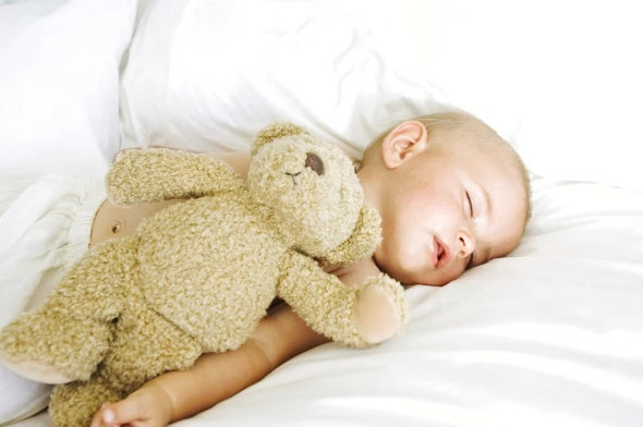Μωρό που απολαμβάνει έναν υπνάκο αγκαλιά με το αρκούδι του